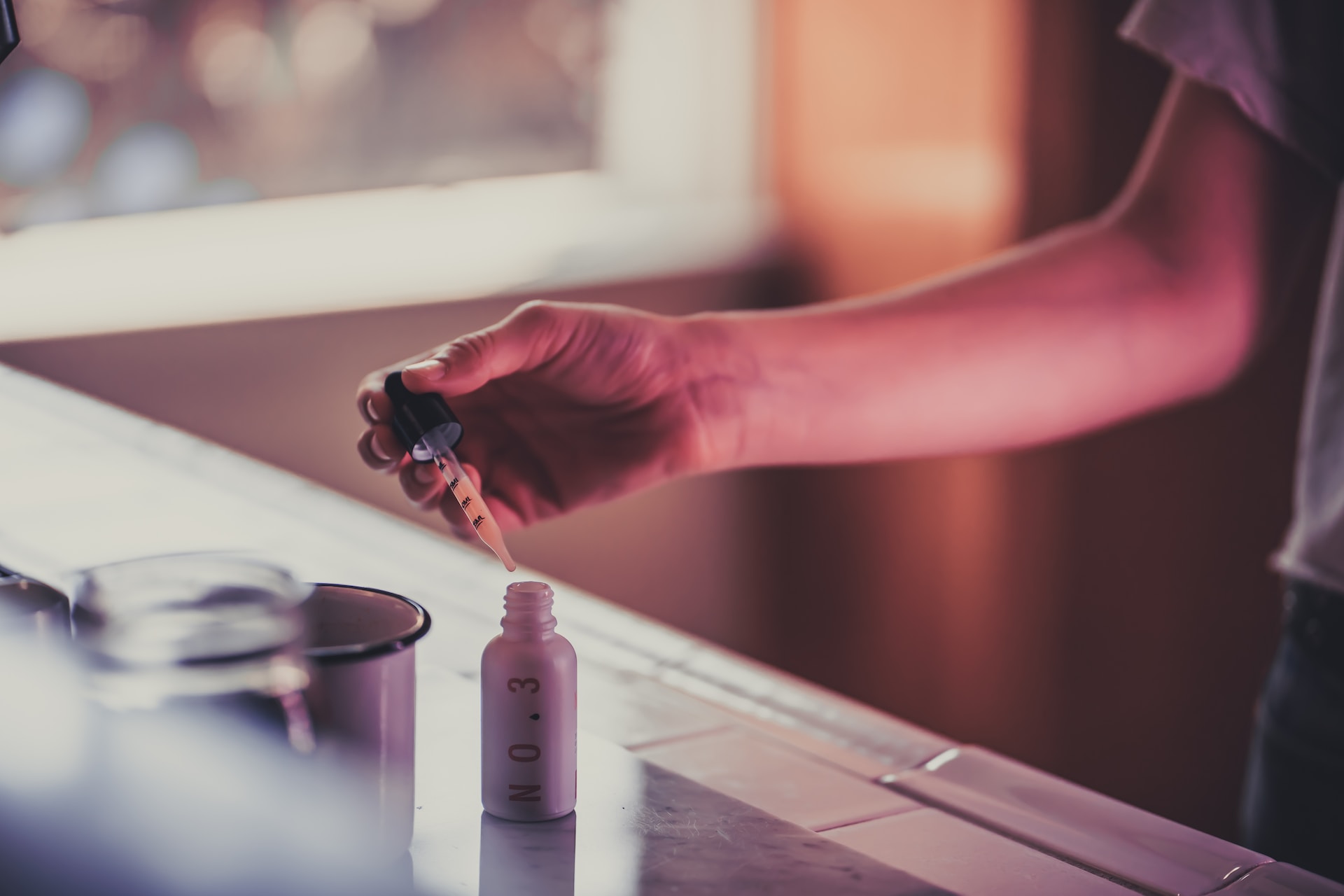 person using a dropper bottle at the counter