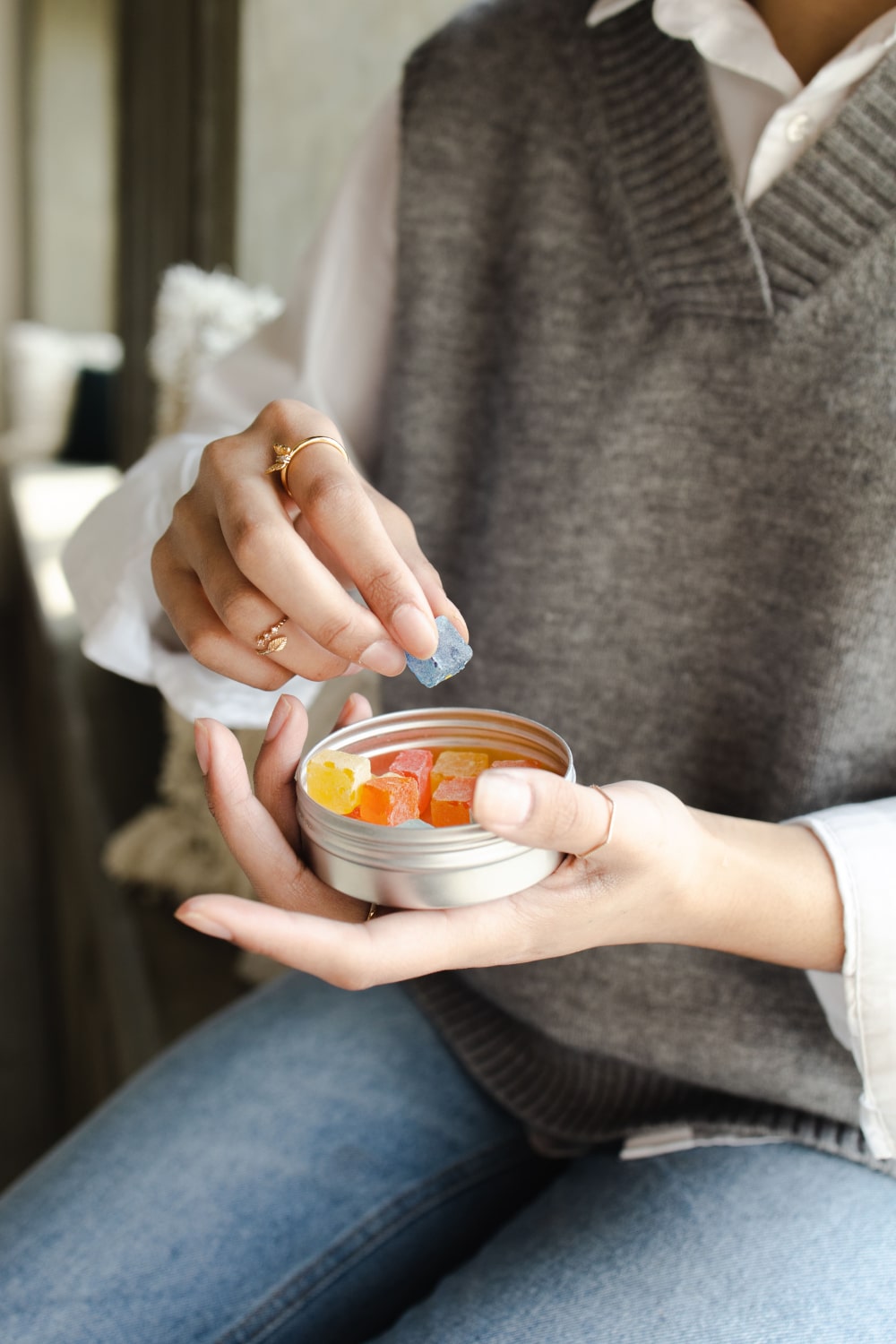 Woman picking up edible gummy from tin